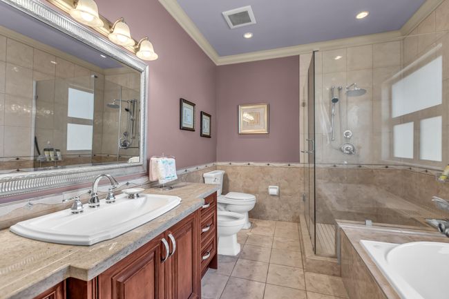 Full bathroom featuring a bidet, toilet, vanity, a stall shower, and tile walls | Image 21