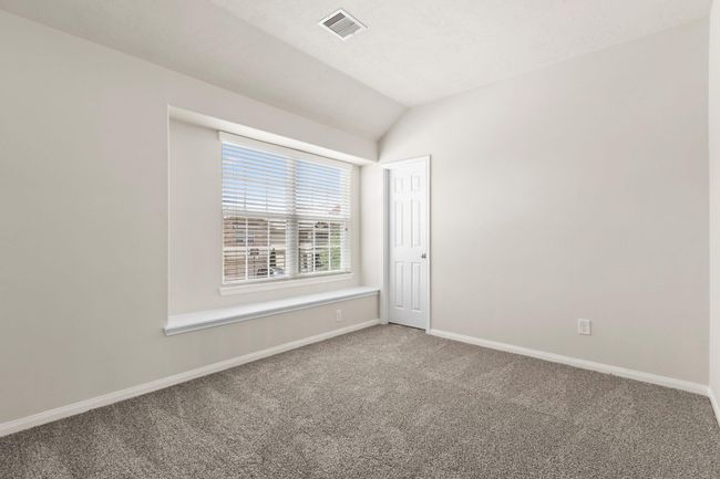 Bright room with neutral walls and carpet, featuring a large window with blinds. There's a small closet door and a ledge beneath the window, creating a cozy nook. | Image 24