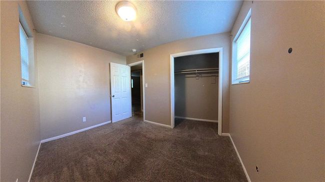 Unfurnished bedroom with dark colored carpet, a textured ceiling, and a closet | Image 5