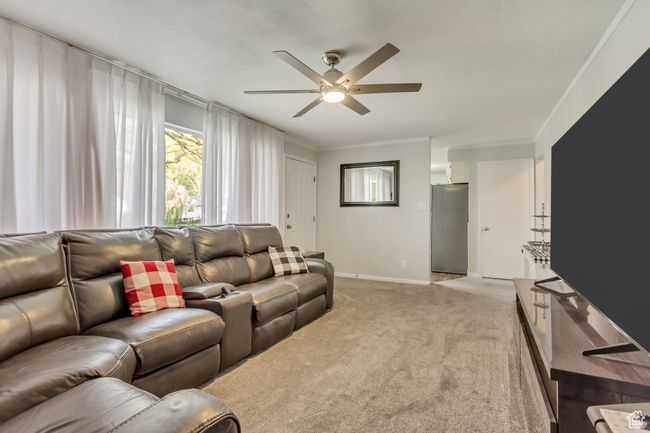 Living room with ceiling fan, baseboards, ornamental molding, and light carpet | Image 5