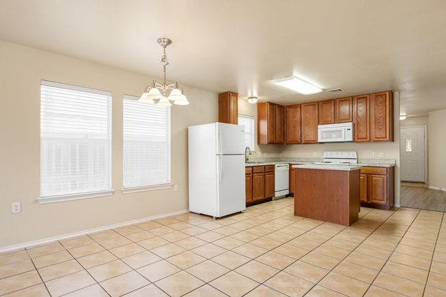 Kitchen with white appliances, light countertops, a chandelier, and plenty of natural light | Image 11