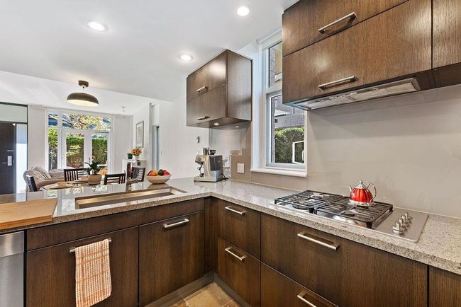 Kitchen with recessed lighting, stainless steel gas stovetop, light stone countertops, and dark brown cabinetry, high end appliances, large sized sink. | Image 23