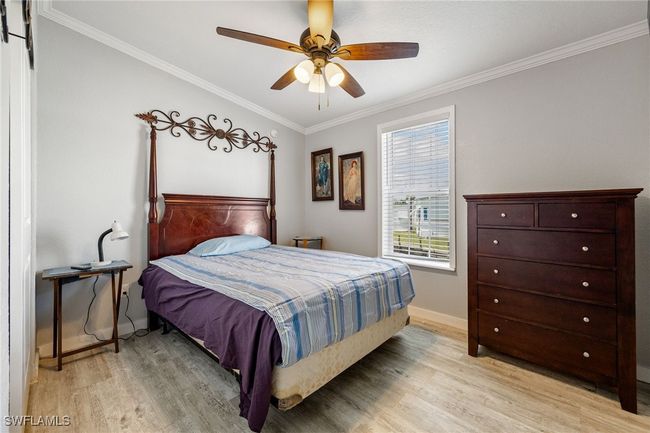 Bedroom with ornamental molding, light wood finished floors, a ceiling fan, and baseboards | Image 23