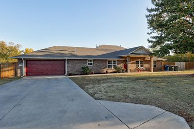 Ranch-style house with a front yard and a garage | Image 1