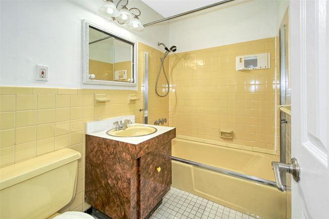 Full hall bathroom featuring vanity, washtub / shower combination, tile walls, tile patterned flooring, and wainscoting | Image 15