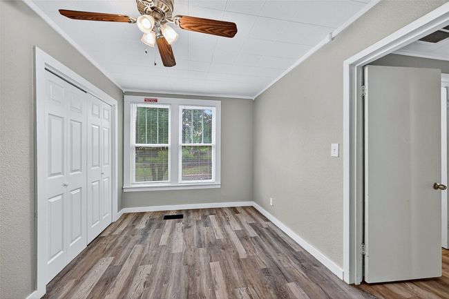 Unfurnished bedroom featuring ornamental molding, wood finished floors, a closet, ceiling fan, and a textured wall | Image 18
