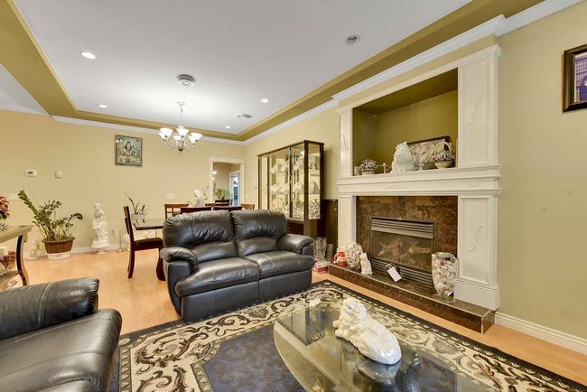 Living area featuring wood finished floors, a chandelier, baseboards, a fireplace, and crown molding | Image 40