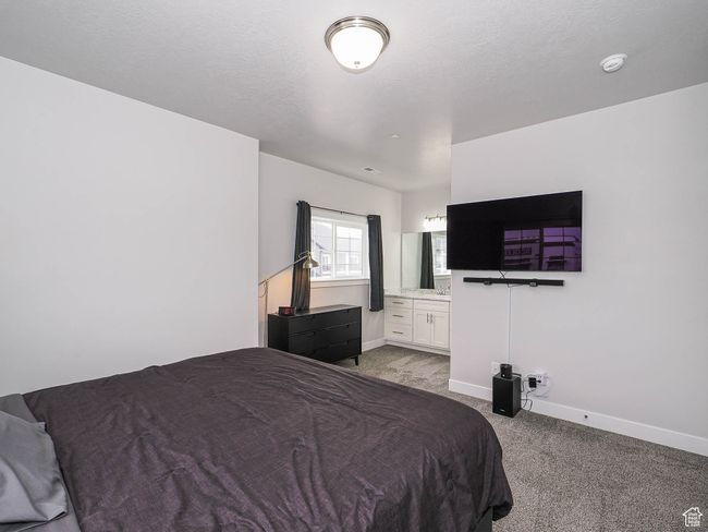 Bedroom featuring baseboards, a textured ceiling, ensuite bathroom, and light colored carpet | Image 21