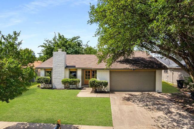 View of front of home with brick siding, driveway, a garage, and a front yard | Image 16