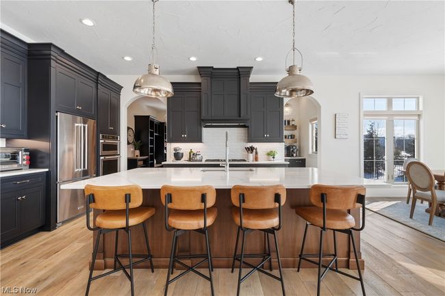 Kitchen with a center island with sink, light wood-type flooring, and hanging light fixtures | Image 9