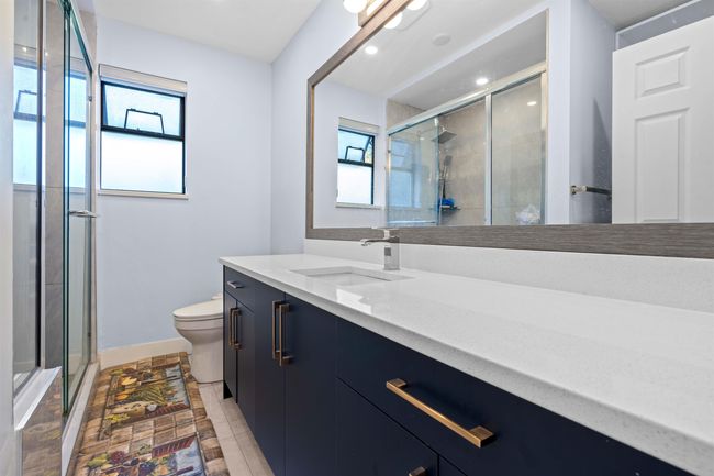 Bathroom featuring a stall shower, toilet, baseboards, recessed lighting, and vanity | Image 34