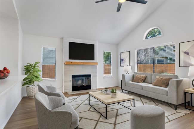Living room featuring wood finished floors, a ceiling fan, a tiled fireplace, and high vaulted ceiling | Image 6