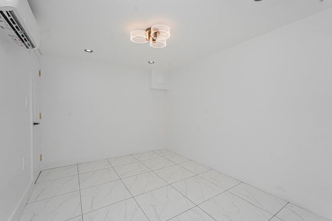 Empty room with an AC wall unit, light marble finish flooring, recessed lighting, and a chandelier | Image 13