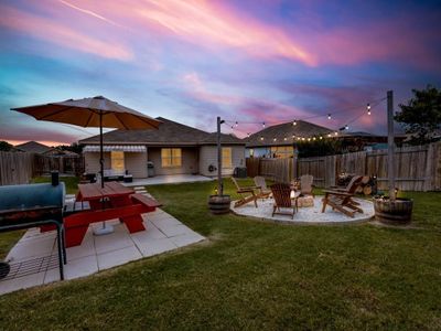 Yard at dusk with large covered patio, fire pit and picnic area | Image 1