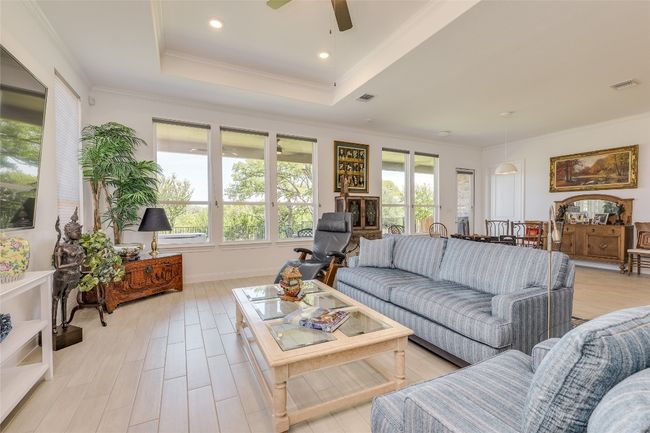 Living room with a tray ceiling, crown molding, light wood finished floors, recessed lighting, and a ceiling fan | Image 11