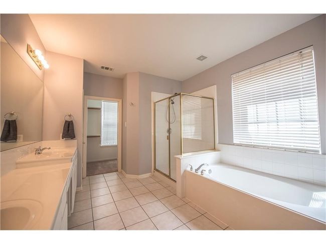 Full bath featuring a garden tub, tile patterned flooring, a stall shower, double vanity, and baseboards | Image 17