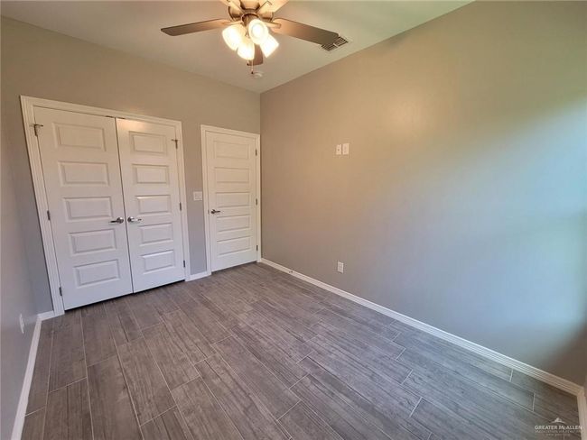 Unfurnished bedroom featuring dark wood-style floors, baseboards, visible vents, and a closet | Image 9