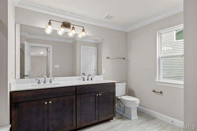 Bathroom with double vanity, toilet, baseboards, and ornamental molding | Image 16