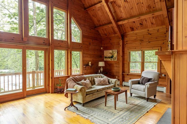 Living area with a baseboard radiator, wooden ceiling with exposed beams, wood finished floors, wood walls, and high vaulted ceiling | Image 10
