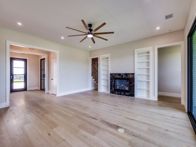 Unfurnished living room with ceiling fan, baseboards, built in shelves, light wood-style floors, and recessed lighting | Image 15