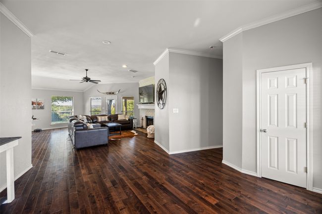 Living area featuring dark wood-style floors, crown molding, visible vents, and a fireplace | Image 8