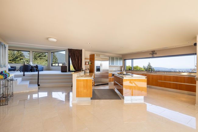 Kitchen with modern cabinets, light tile patterned floors, brown cabinetry, a kitchen island, and appliances with stainless steel finishes | Image 5