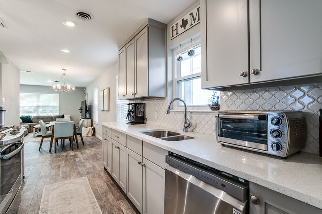Kitchen featuring stainless steel appliances, a sink, gray cabinetry, a chandelier, and hardwood / wood-style flooring | Image 12