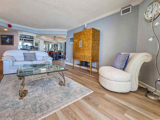 Living room featuring crown molding, ornate columns, a textured ceiling, and wood finished floors | Image 6