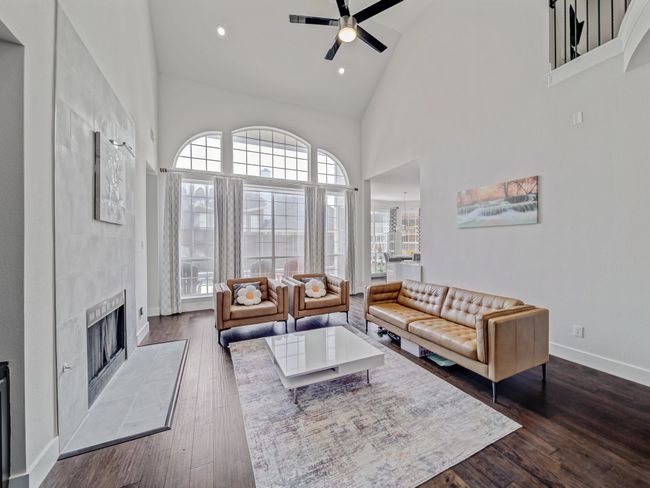 Living area featuring high vaulted ceiling, ceiling fan, baseboards, dark wood-style floors, and a tile fireplace | Image 6
