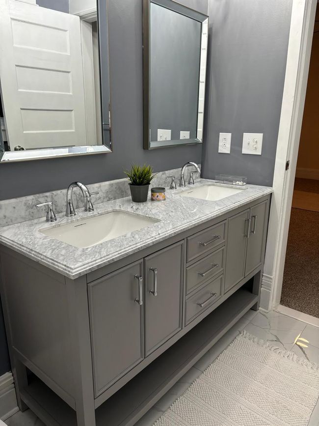 Bathroom with double vanity, marble look tiles, and baseboards | Image 7