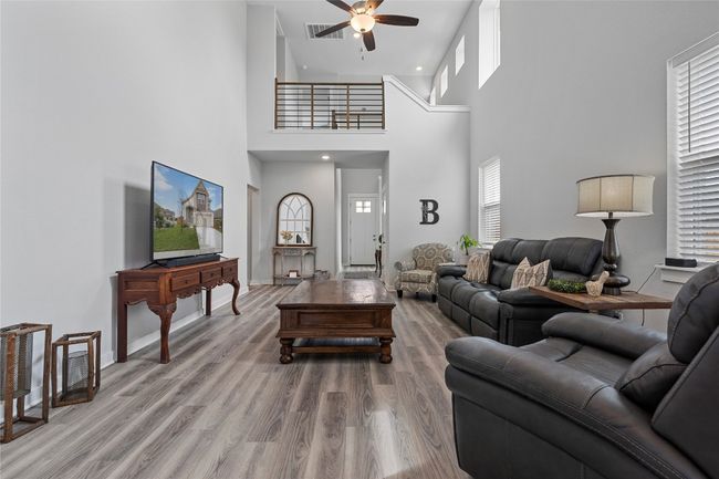 Living room featuring ceiling fan, a high ceiling, wood finished floors, recessed lighting, and baseboards | Image 9