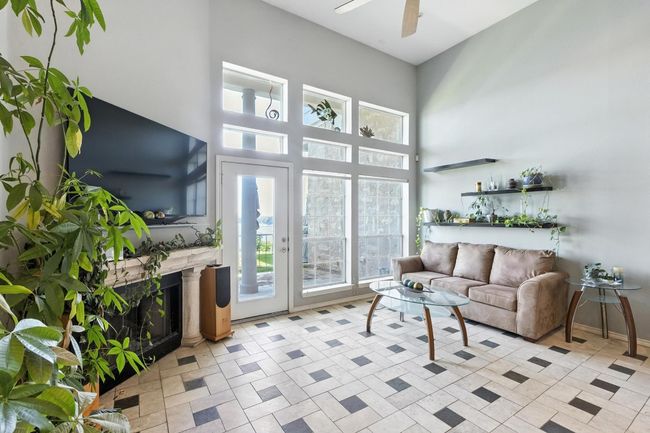 Living area with a fireplace, ceiling fan, and a towering ceiling | Image 12
