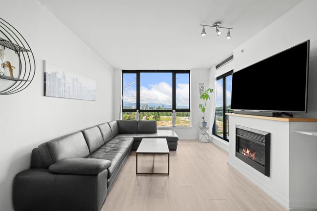 Living area with light wood finished floors and a glass covered fireplace | Image 4