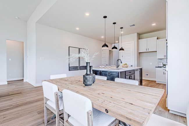 The dining area offers a seamless connection to the kitchen and island bar seating, all wrapped in soft light from the oversized windows. | Image 16