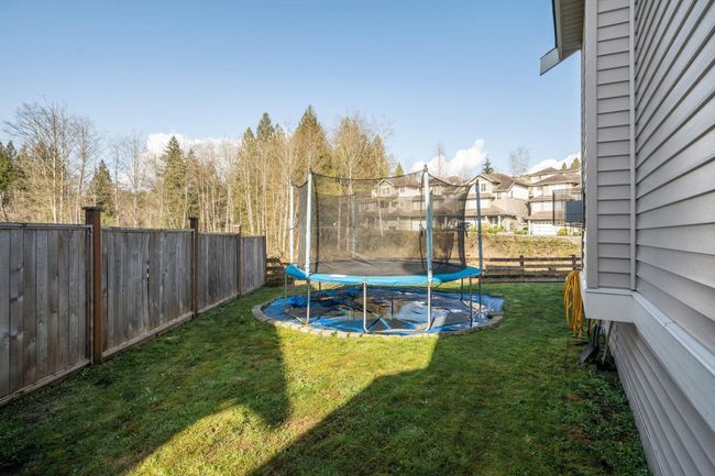 View of yard featuring a trampoline, a fenced backyard, and a residential view | Image 40