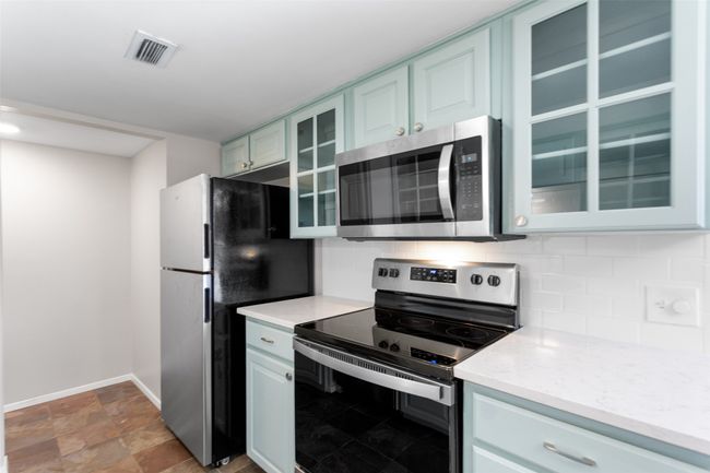Kitchen with light stone countertops, appliances with stainless steel finishes, baseboards, tasteful backsplash, and glass insert cabinets | Image 15