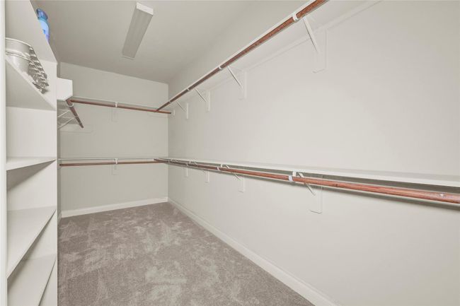 Two large, full-entry closets in the primary suite both offer thoughtful custom shelving, ample hanging space, and plush carpet underfoot—every detail designed for ease and comfort. | Image 27