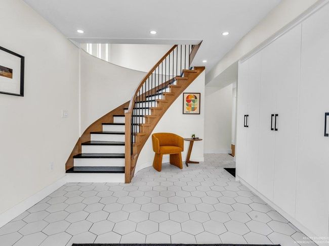 All newly renovated, gorgeous bright foyer with ultra modern front door, built in wall of brand new white cabinetry with black hardware, stunning honeycomb tiling, new staircase risers, treads and beautiful railing. | Image 6