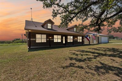 View of front of house featuring a lawn, a porch, and a garage | Image 1