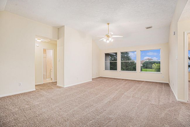 Spacious upstairs game room with new carpet, ceiling fans and lots of windows with pull down attic stairs in hallway to the left. | Image 29
