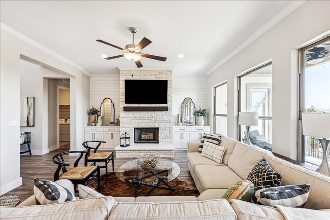 The main focal point of the room is the floor-to-ceiling stone fireplace with a raised hearth and cedar mantle, while custom cabinets with shiplap wall panels on both sides add warmth and charm. | Image 10