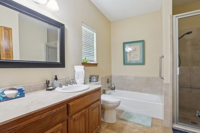 Bathroom featuring tile patterned flooring, vanity, toilet, a stall shower, and a bath | Image 14