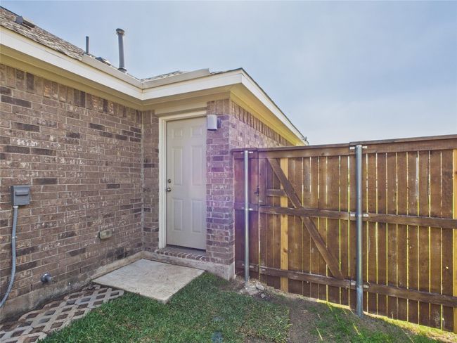 Doorway to property featuring brick siding and fence | Image 18