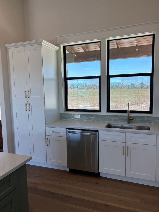 Kitchen featuring dishwashing machine, a sink, dark wood finished floors, and white cabinetry | Image 23