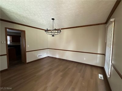 Unfurnished dining area with a textured ceiling, dark hardwood / wood-style flooring, and crown molding | Image 3