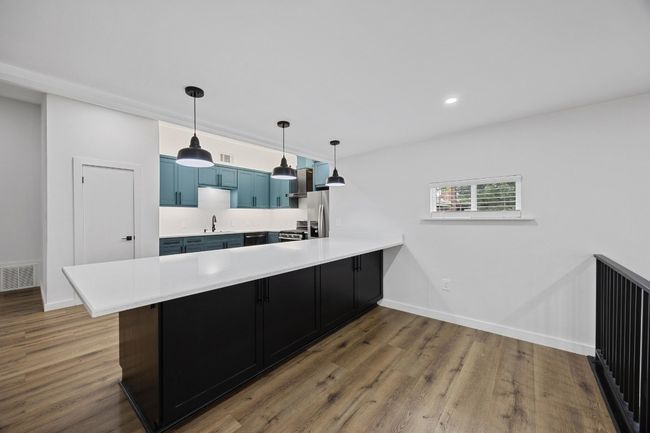 Kitchen with a peninsula, light countertops, dark wood-type flooring, blue cabinets, and recessed lighting | Image 14