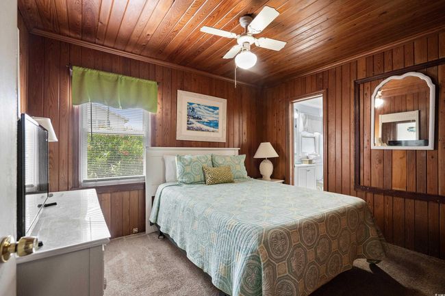 Bedroom with light carpet, wooden walls, wood ceiling, ceiling fan, and connected bathroom | Image 13