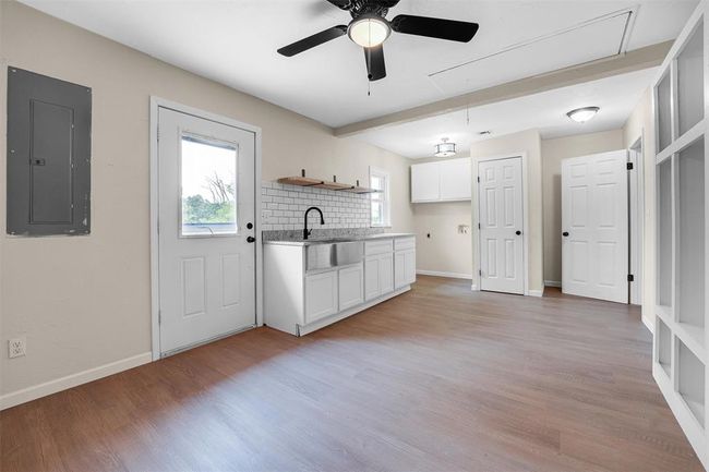 Kitchen featuring ceiling fan, decorative backsplash, sink, light hardwood / wood-style floors, and electric panel | Image 40