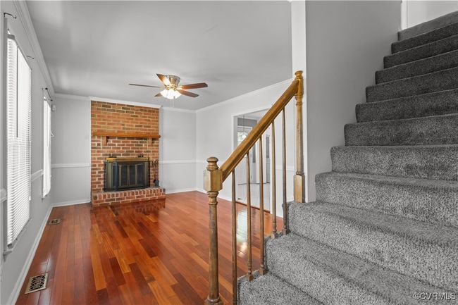 Stairs featuring wood finished floors, visible vents, ornamental molding, and ceiling fan | Image 6