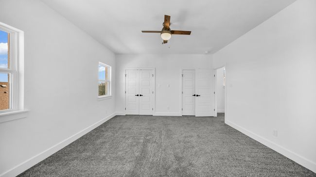 Unfurnished bedroom featuring a ceiling fan, baseboards, and dark colored carpet | Image 27